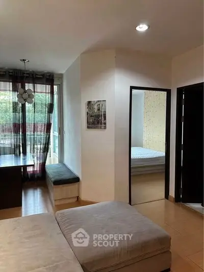 Cozy living room with natural light and view into a bedroom, featuring modern decor.