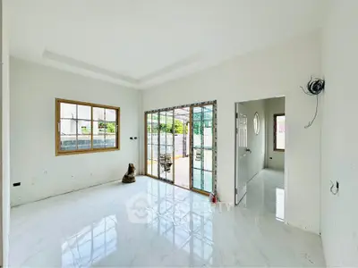 Bright and spacious room with large windows and sliding glass doors leading to a patio.