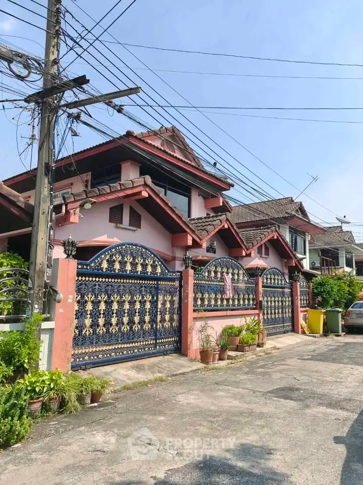 Charming suburban house with ornate gate and lush greenery, perfect for family living.