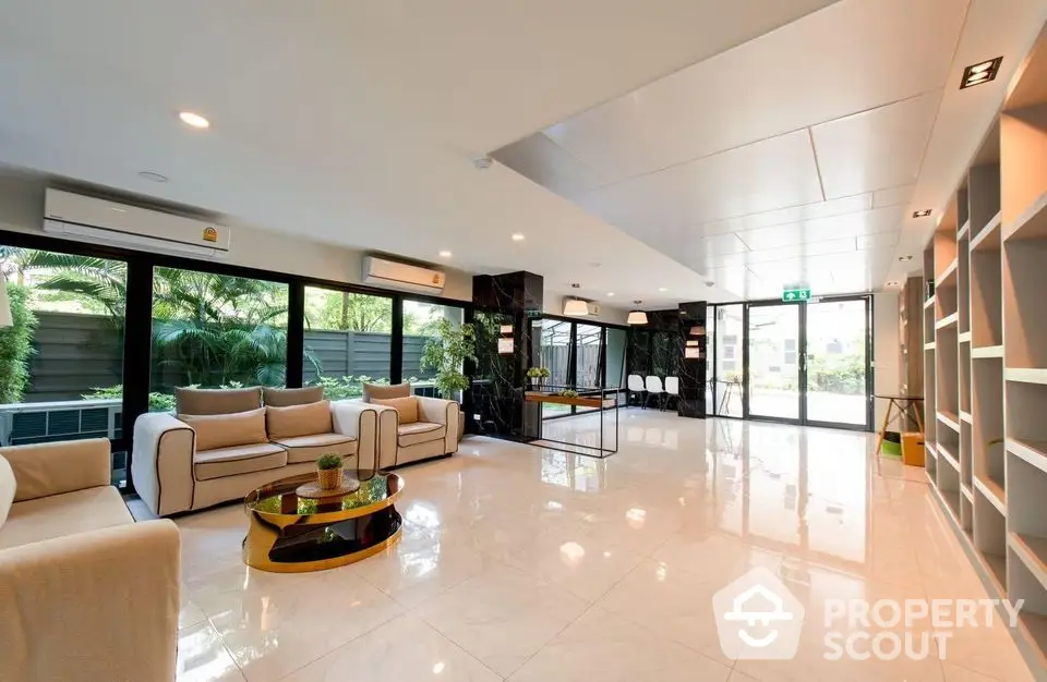 Spacious modern living room with elegant decor and large windows overlooking greenery.