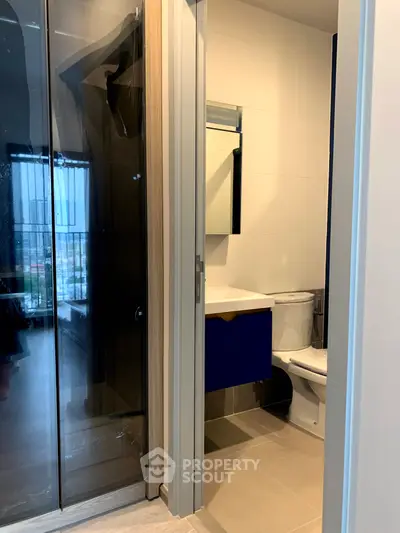 Modern bathroom with sleek design and glass shower door in contemporary apartment.