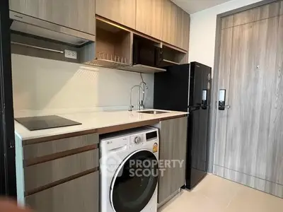 Modern compact kitchen with integrated washing machine and sleek cabinetry.