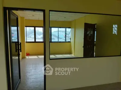 Spacious room with large windows and yellow walls, offering abundant natural light and a view of the neighborhood.