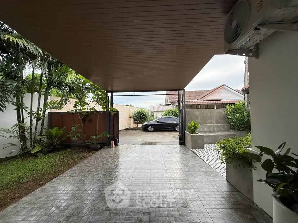 Spacious covered driveway with lush greenery and modern design, perfect for multiple vehicles.