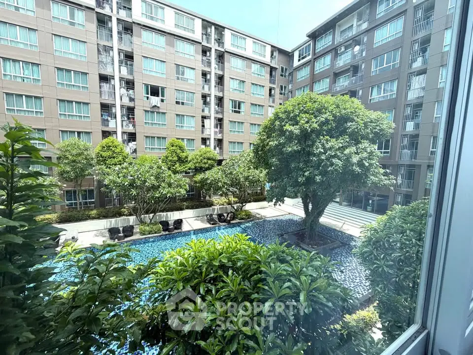 Stunning view of modern apartment complex with lush garden and inviting pool area.