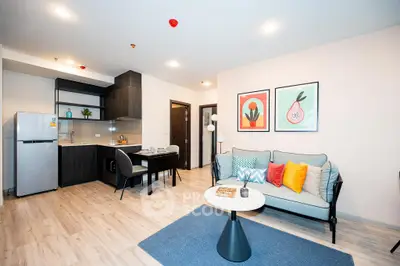 Modern open-layout living room with stylish decor and kitchen area, perfect for urban living.