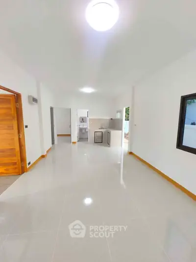 Spacious open-plan living area with modern kitchen and sleek tile flooring.
