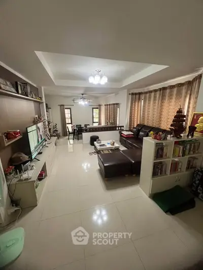 Spacious living room with modern decor and ample natural light, perfect for family gatherings.