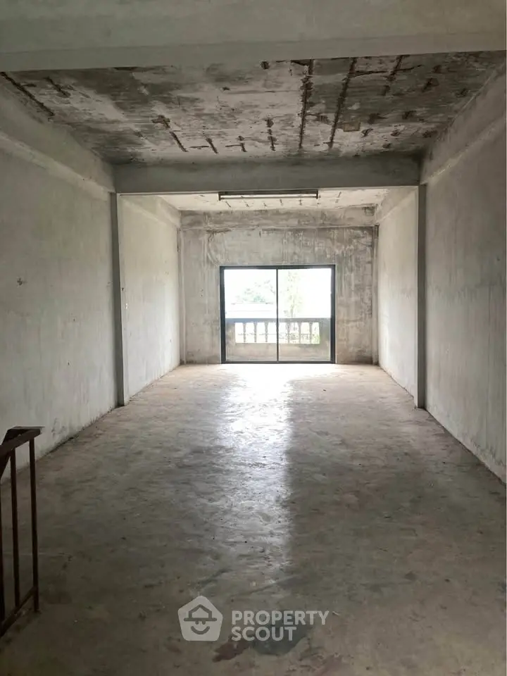 Spacious unfinished room with large window and balcony view, ideal for customization.