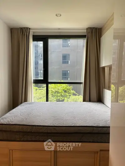 Spacious bedroom with large window offering a serene view, perfect for relaxation and comfort.
