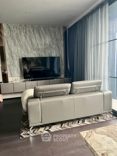 Luxurious living room with modern decor and large TV, featuring floor-to-ceiling windows and elegant furnishings.