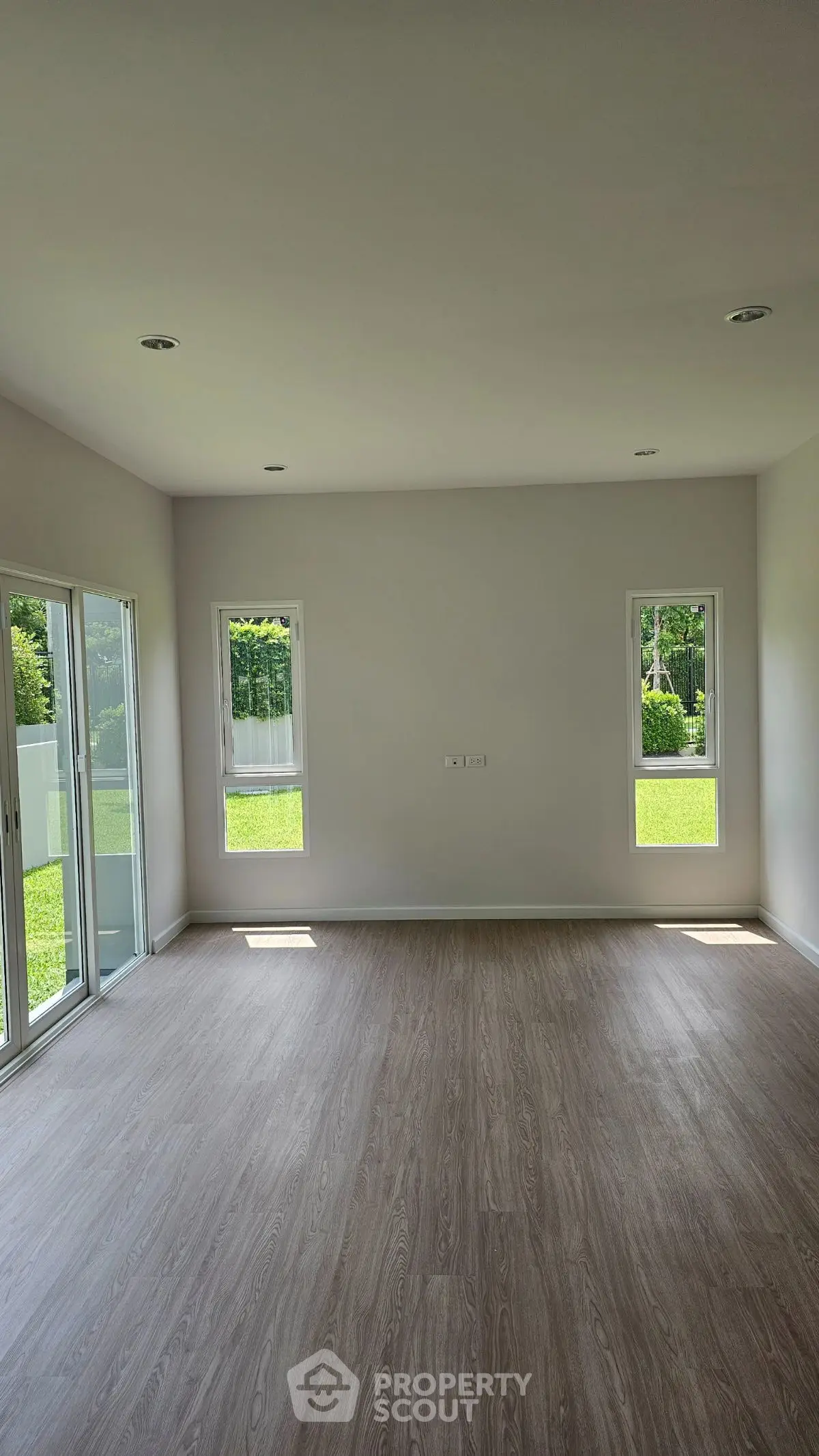 Spacious empty room with large windows and wooden flooring, perfect for customization.