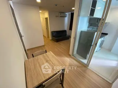 Modern apartment interior with open kitchen and cozy living area, featuring wooden flooring and sleek appliances.
