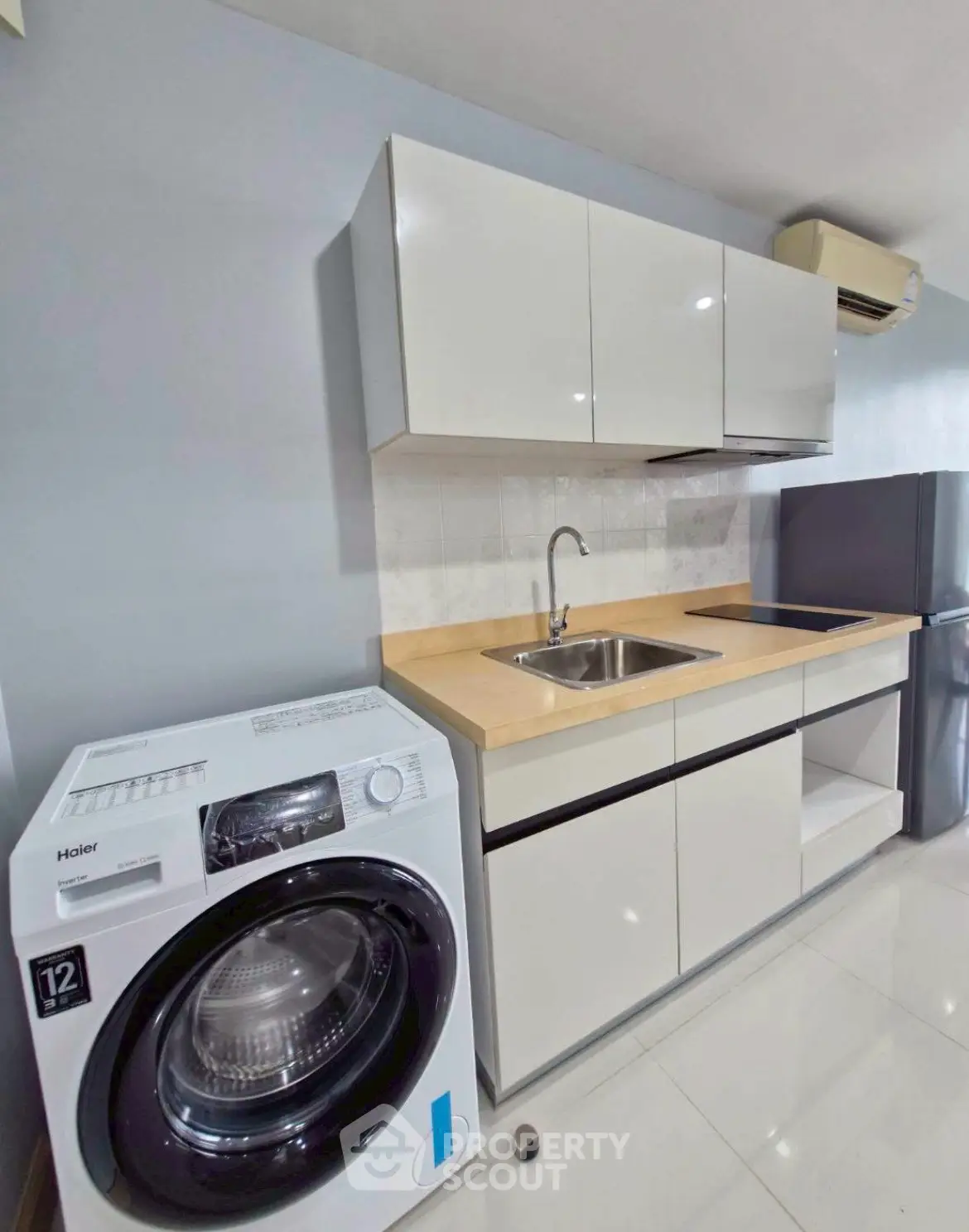 Modern kitchen with sleek cabinets, washing machine, and stainless steel appliances.