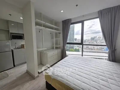 Modern bedroom with city view, open closet, and adjacent kitchen area in a high-rise apartment.