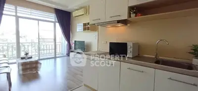 Modern open-plan living room with kitchen, featuring large windows and balcony access.