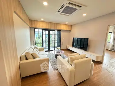 Spacious modern living room with elegant furniture and large TV, featuring natural light and stylish decor.