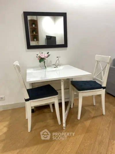 Charming dining nook with white table, chairs, and elegant mirror in cozy living space.