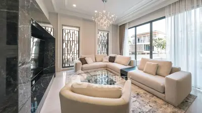 Luxurious modern living room with elegant chandelier and large windows offering natural light.