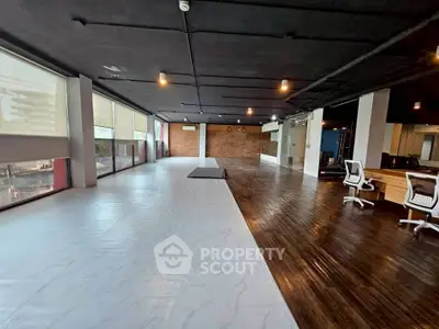 Spacious modern office space with wooden flooring and large windows for natural light.