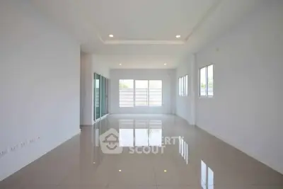Spacious empty living room with glossy tiled floors and large windows offering natural light.