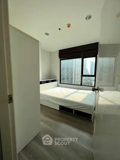 Modern bedroom with large window and city view in high-rise apartment