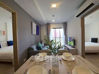 Modern apartment interior with dining table, living room, and bedroom view.