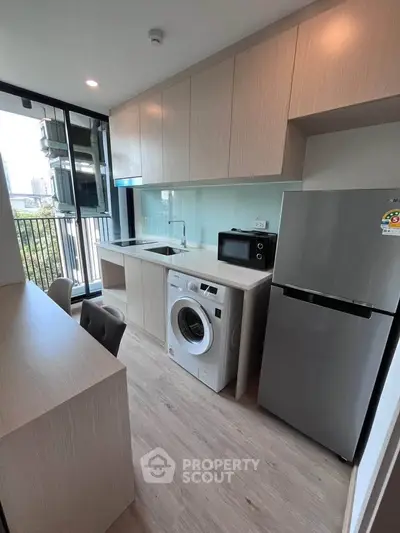 Modern kitchen with sleek appliances and balcony view in urban apartment