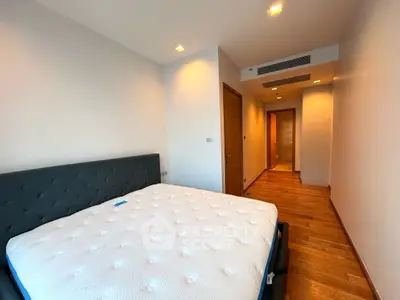 Spacious bedroom with wooden flooring and modern lighting