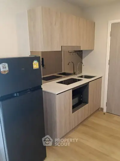 Modern kitchen with sleek cabinetry and double sink in compact apartment.