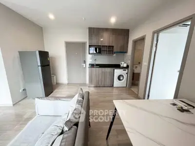 Modern open-plan living room with kitchen, washing machine, and sleek furniture.