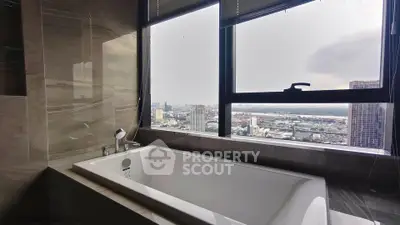 Luxurious bathroom with stunning city view from high-rise apartment window.