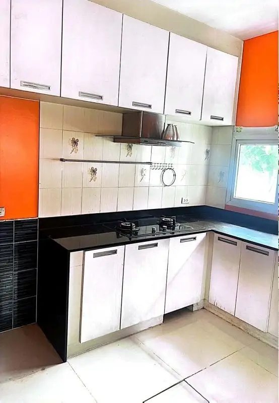 Modern kitchen with sleek cabinets and gas stove, vibrant orange accents, and natural light.