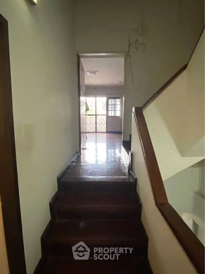 Charming hallway with wooden stairs leading to a bright living area, perfect for cozy family gatherings.