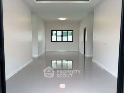 Spacious empty room with glossy tiled flooring and large window, ideal for customization.
