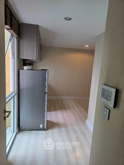 Modern apartment interior with sleek fridge and wooden flooring