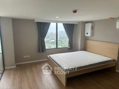 Spacious bedroom with large window offering stunning city views in modern apartment.