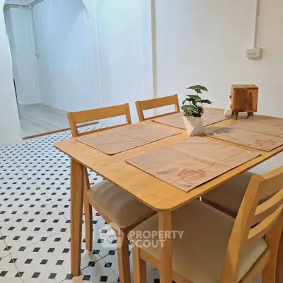 Charming dining area with wooden table and chairs on stylish tiled floor, perfect for cozy meals.