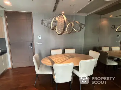 Elegant dining area with modern chandelier and round table in luxurious apartment.