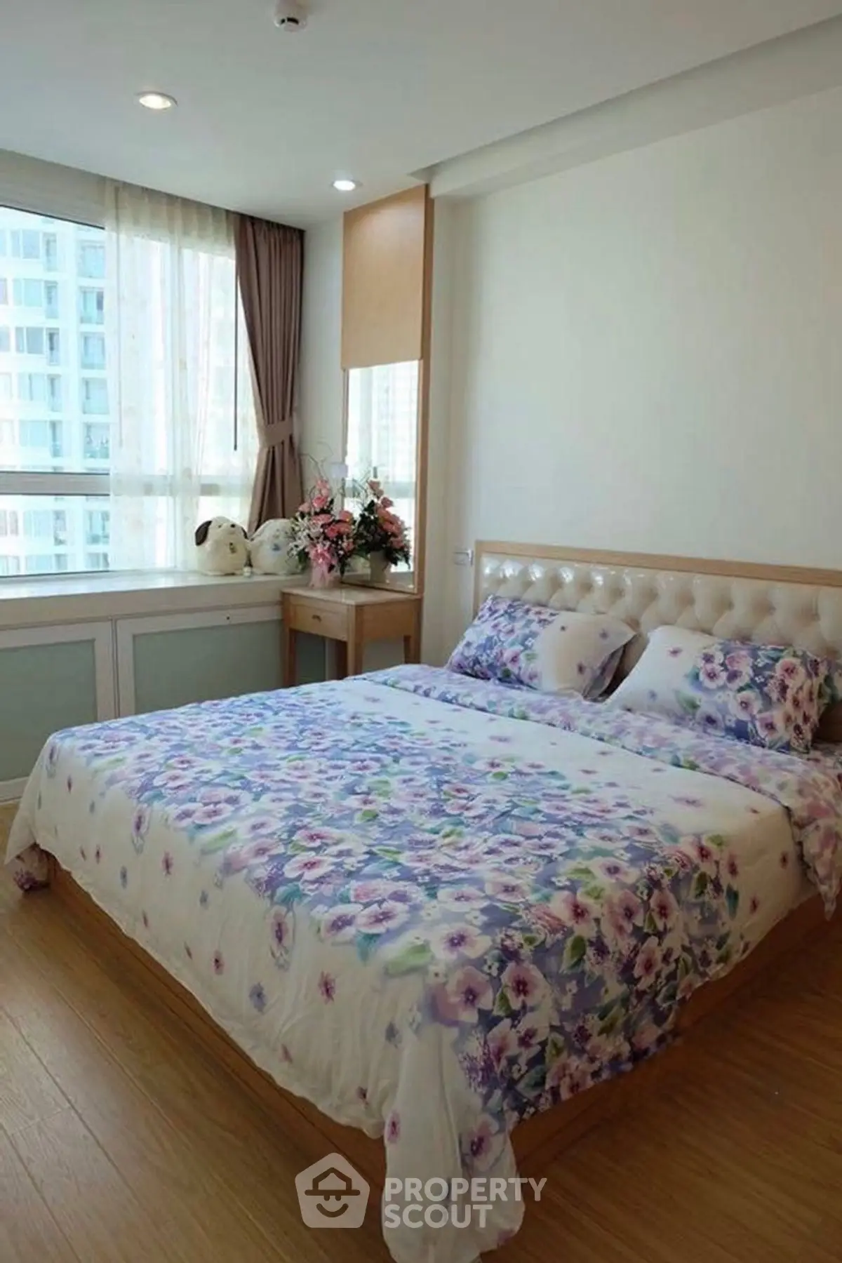 Charming bedroom with floral bedding and city view window in modern apartment.