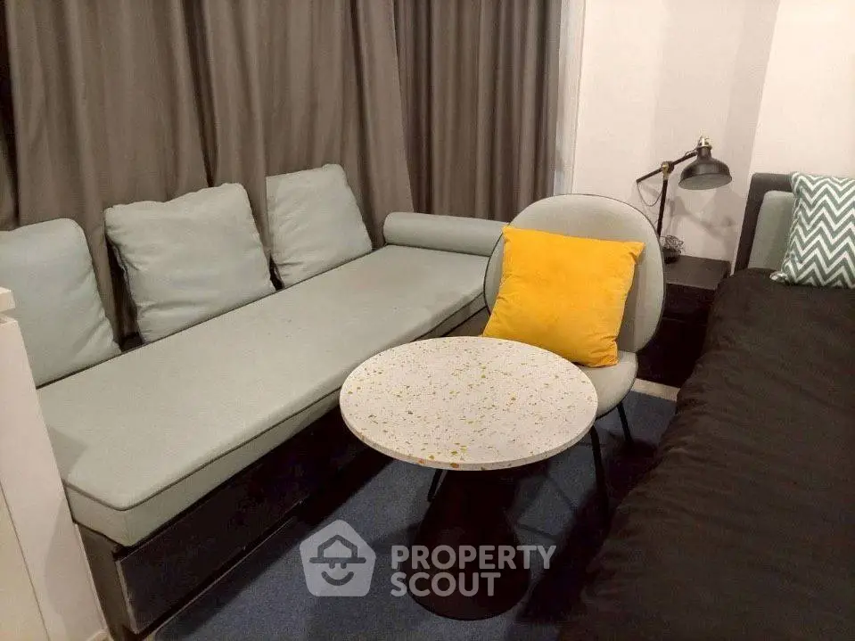 Cozy living room with modern sofa, stylish chair, and accent pillows for a comfortable ambiance.