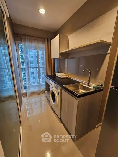 Modern kitchen with washing machine and sleek cabinetry in high-rise apartment