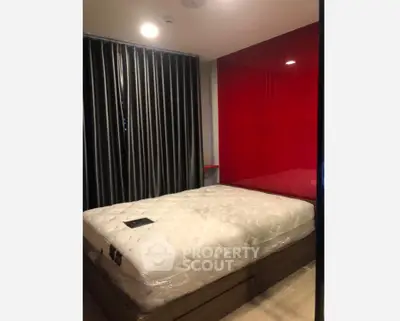 Modern bedroom with red accent wall and stylish curtains, featuring a comfortable bed.