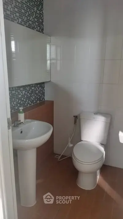 Modern bathroom with pedestal sink and toilet, featuring stylish tile accents.