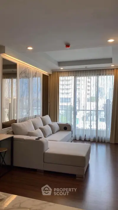 Spacious living room with modern sofa and large windows offering natural light.