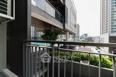 Modern urban balcony with cityscape view, featuring sleek railing and lush greenery.