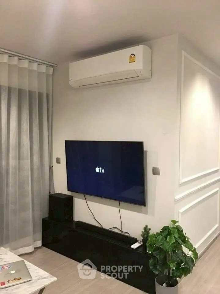 Modern living room with wall-mounted TV and air conditioning unit, stylish decor.