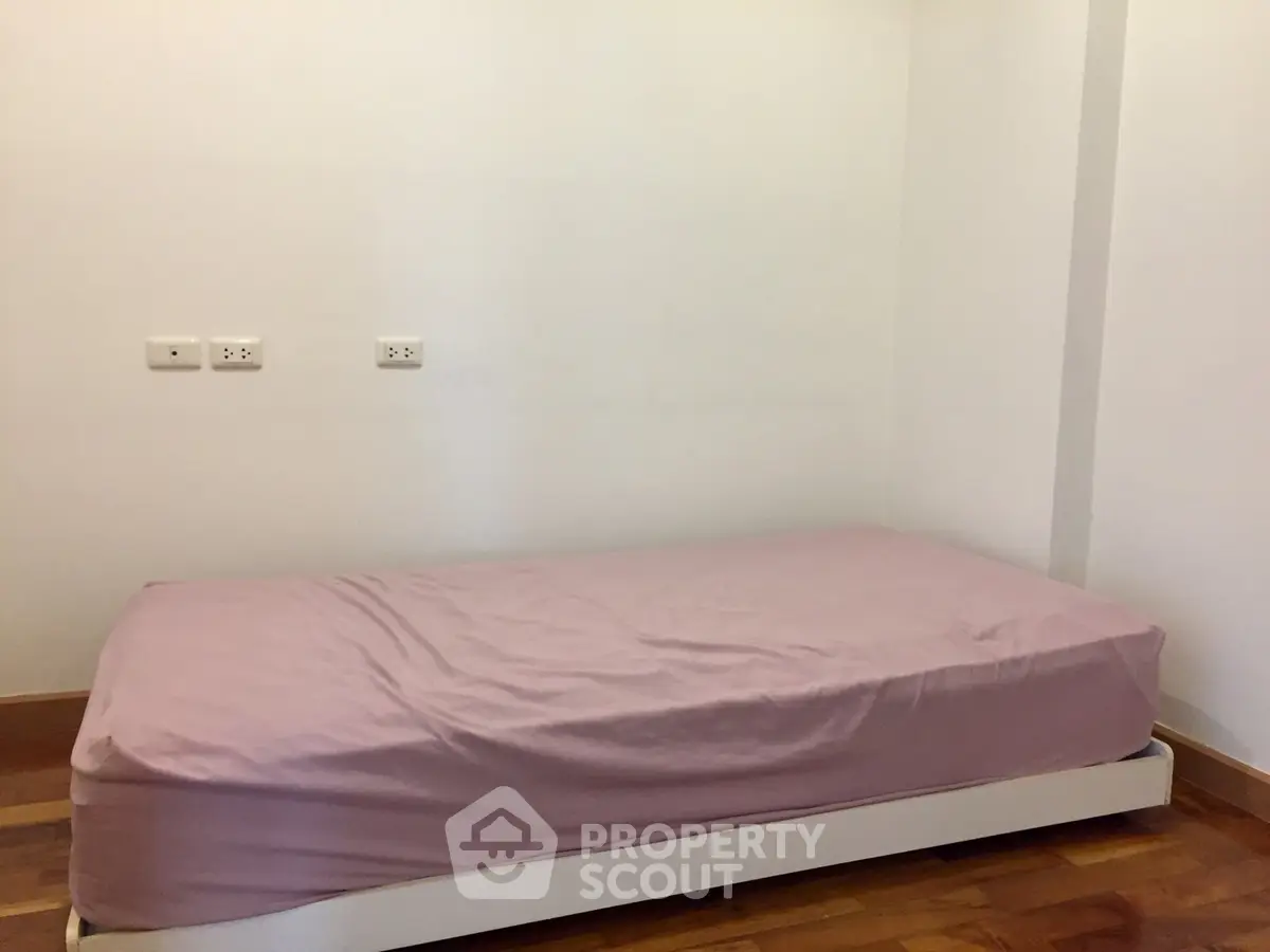 Cozy minimalist bedroom with single bed and wooden flooring, ideal for compact living spaces.