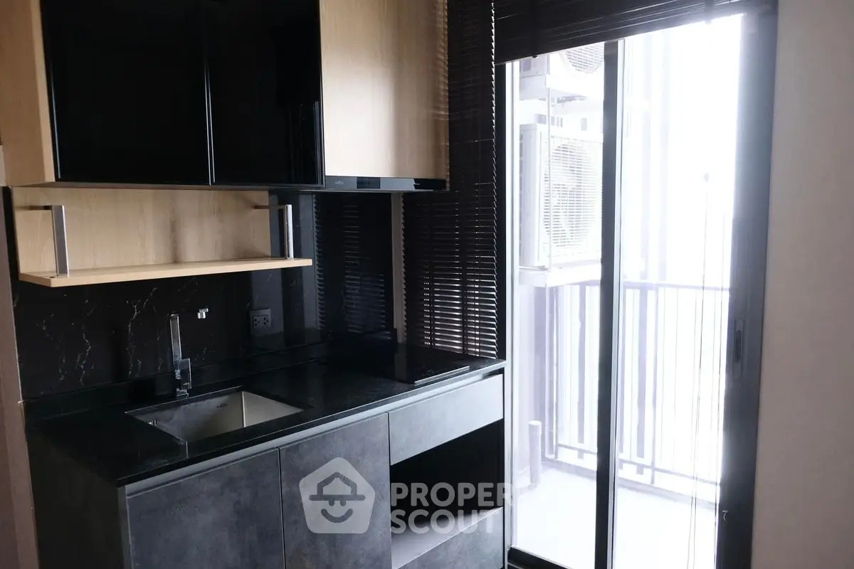Modern kitchen with sleek black countertops and balcony view