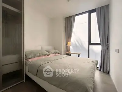 Modern bedroom with large window and stylish decor in a contemporary apartment.